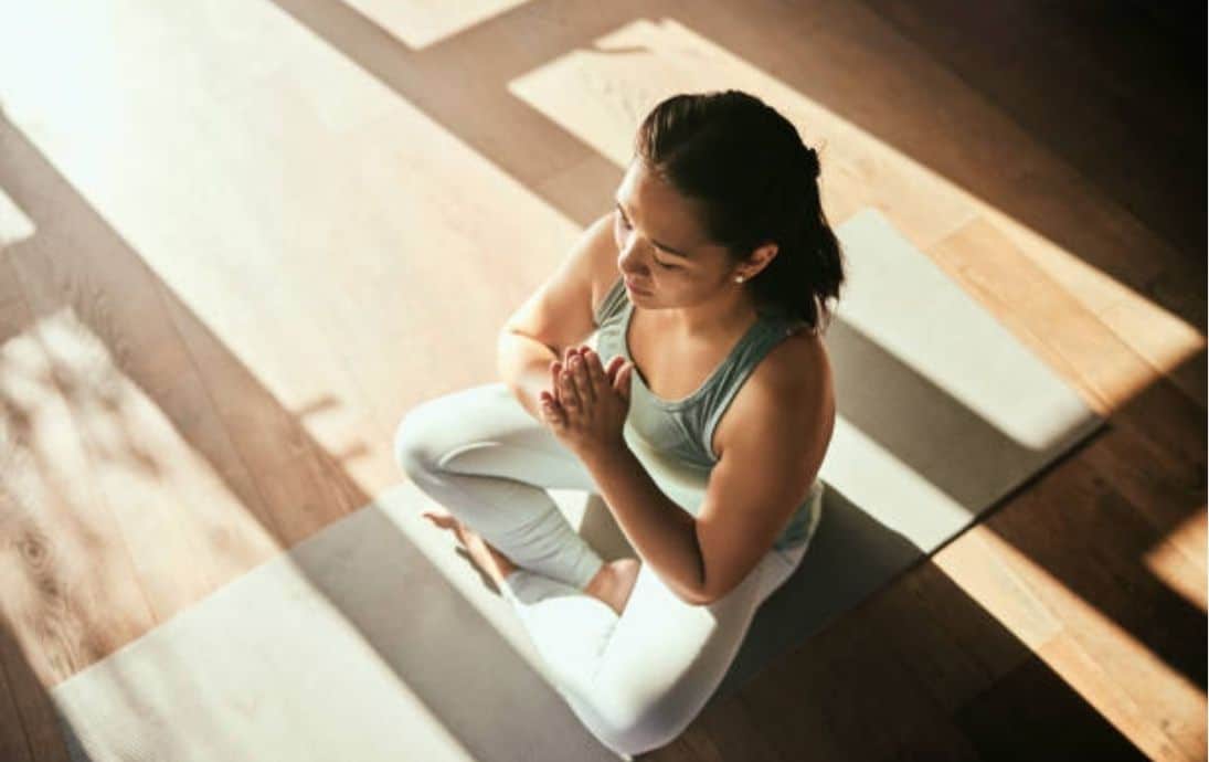 Yoga practitioner in a meditative pose on a yoga mat, promoting mindfulness and wellness.
